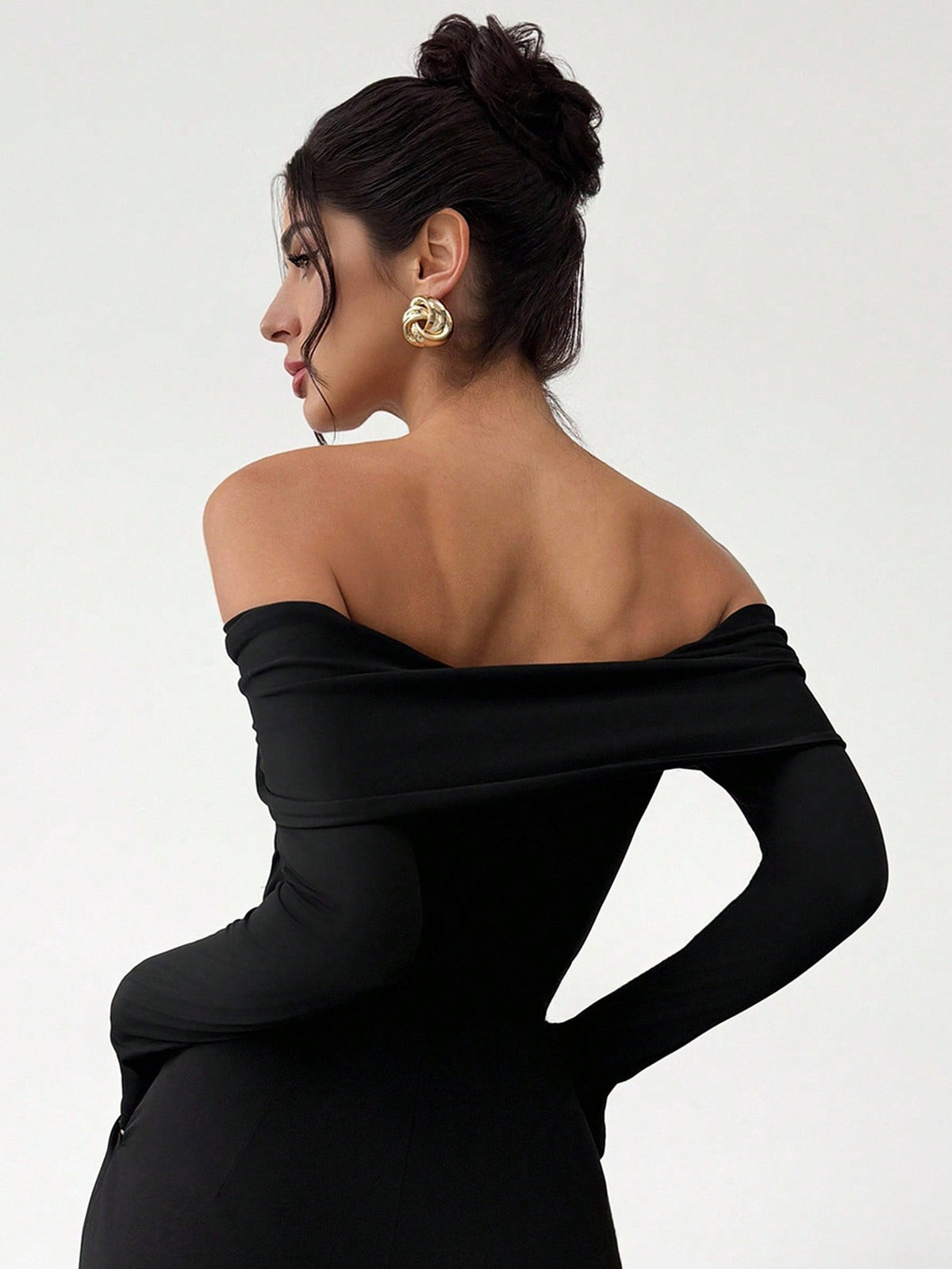 Woman wearing a black off-shoulder dress with a plain background