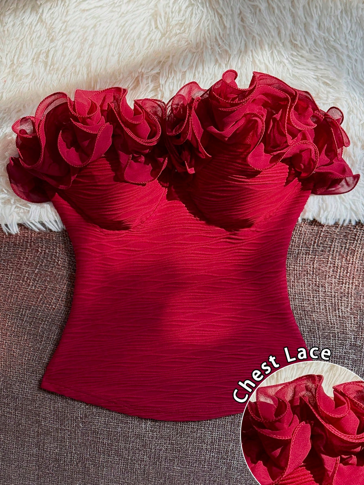 A bright red strapless corset-style top with dramatic ruffled lace detailing across the bust, laid flat on a textured brown surface with a white faux-fur backdrop. A circular inset at the bottom right shows a close-up of the lace fabric, and the text 'Chest Lace' appears near the lower right.