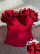 A bright red strapless corset-style top with dramatic ruffled lace detailing across the bust, laid flat on a textured brown surface with a white faux-fur backdrop. A circular inset at the bottom right shows a close-up of the lace fabric, and the text 'Chest Lace' appears near the lower right.
