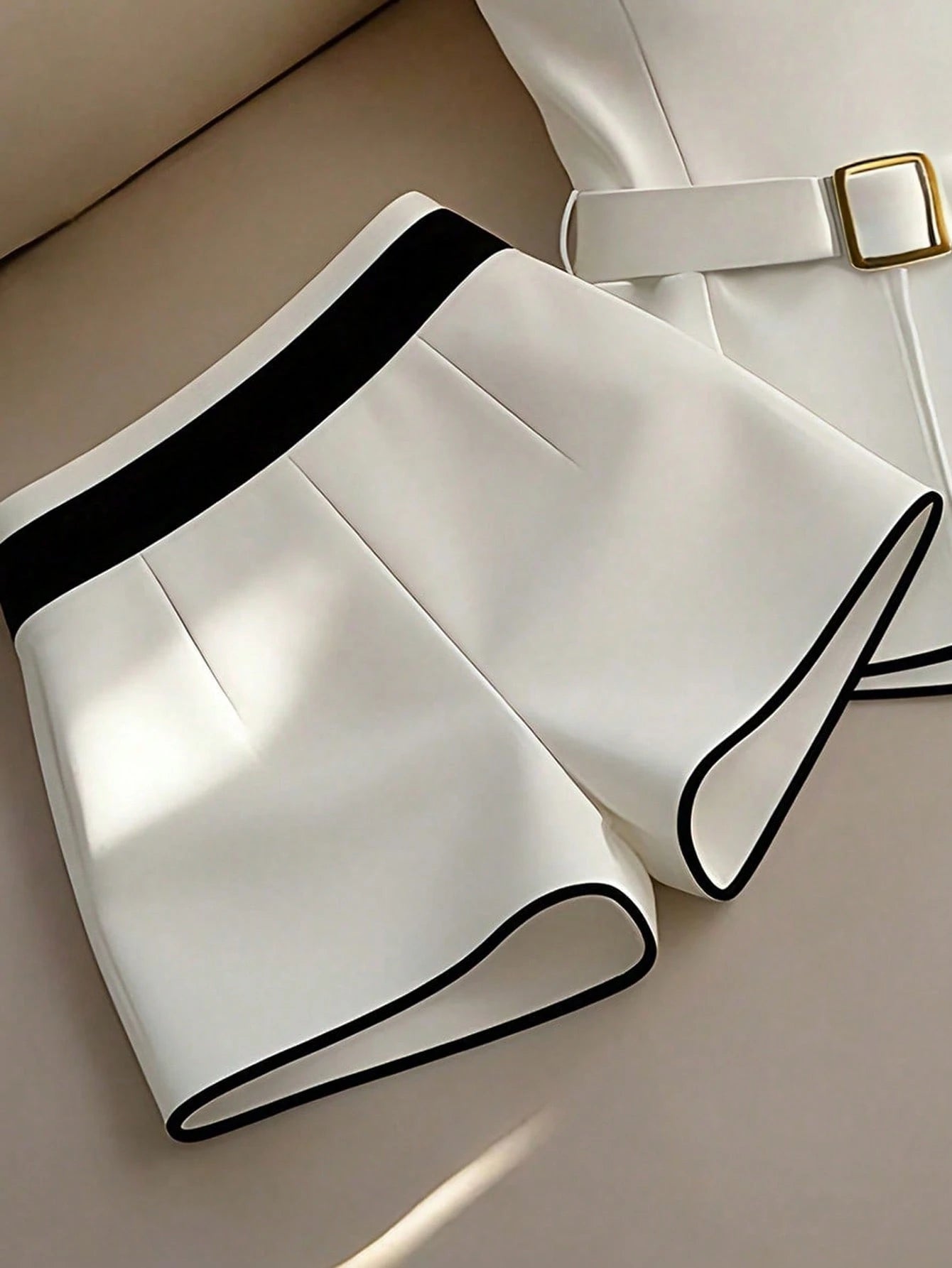 White shorts with black trim on a beige surface
