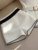 White shorts with black trim on a beige surface