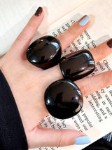 Black stones held in a hand with a blurred book in the background