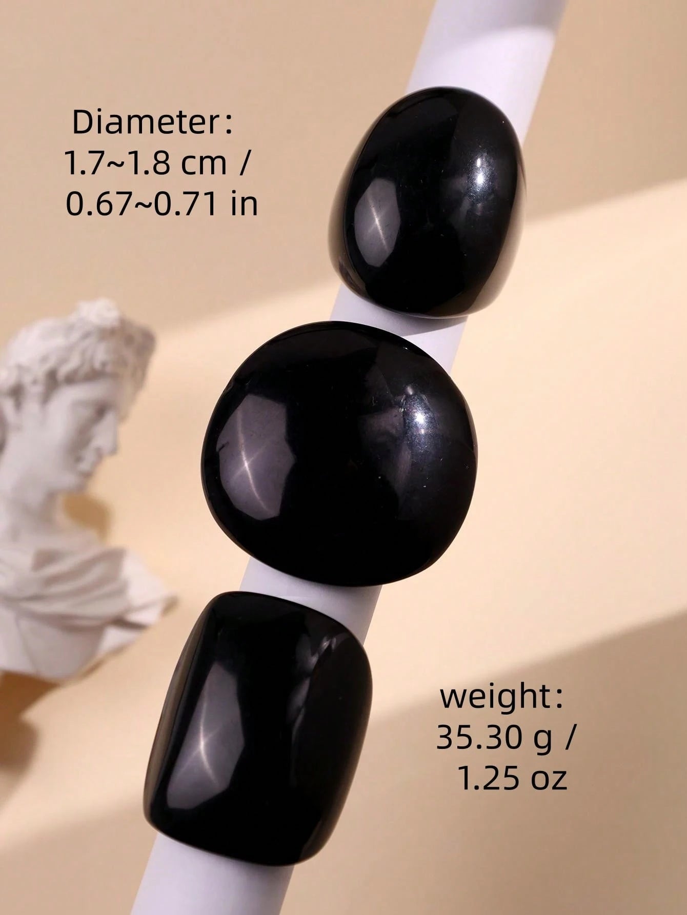 Black cylindrical objects on a white stand with measurements and weight details on a beige background