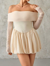 Woman wearing a beige off-shoulder top and skirt with sheer sleeves against a gray background