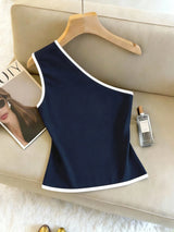 Navy blue sleeveless top on a hanger with a magazine and perfume bottle on a beige surface.