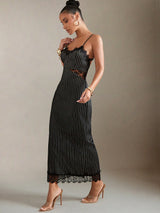Woman wearing a black pinstripe dress with lace details on a neutral background