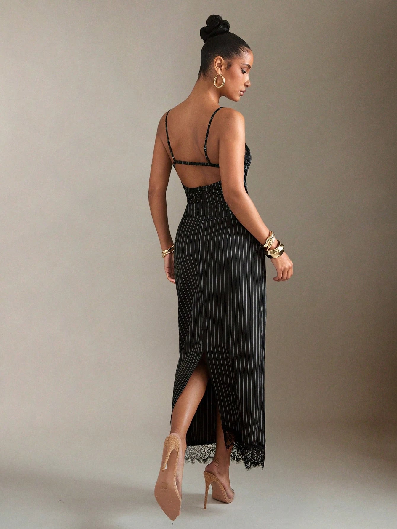 Woman wearing a black dress with a high slit on a plain background