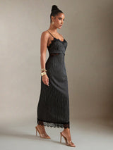 Woman wearing a black dress with thin straps against a neutral background