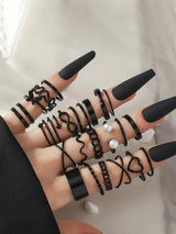 Close-up of a hand with multiple black rings on a neutral background