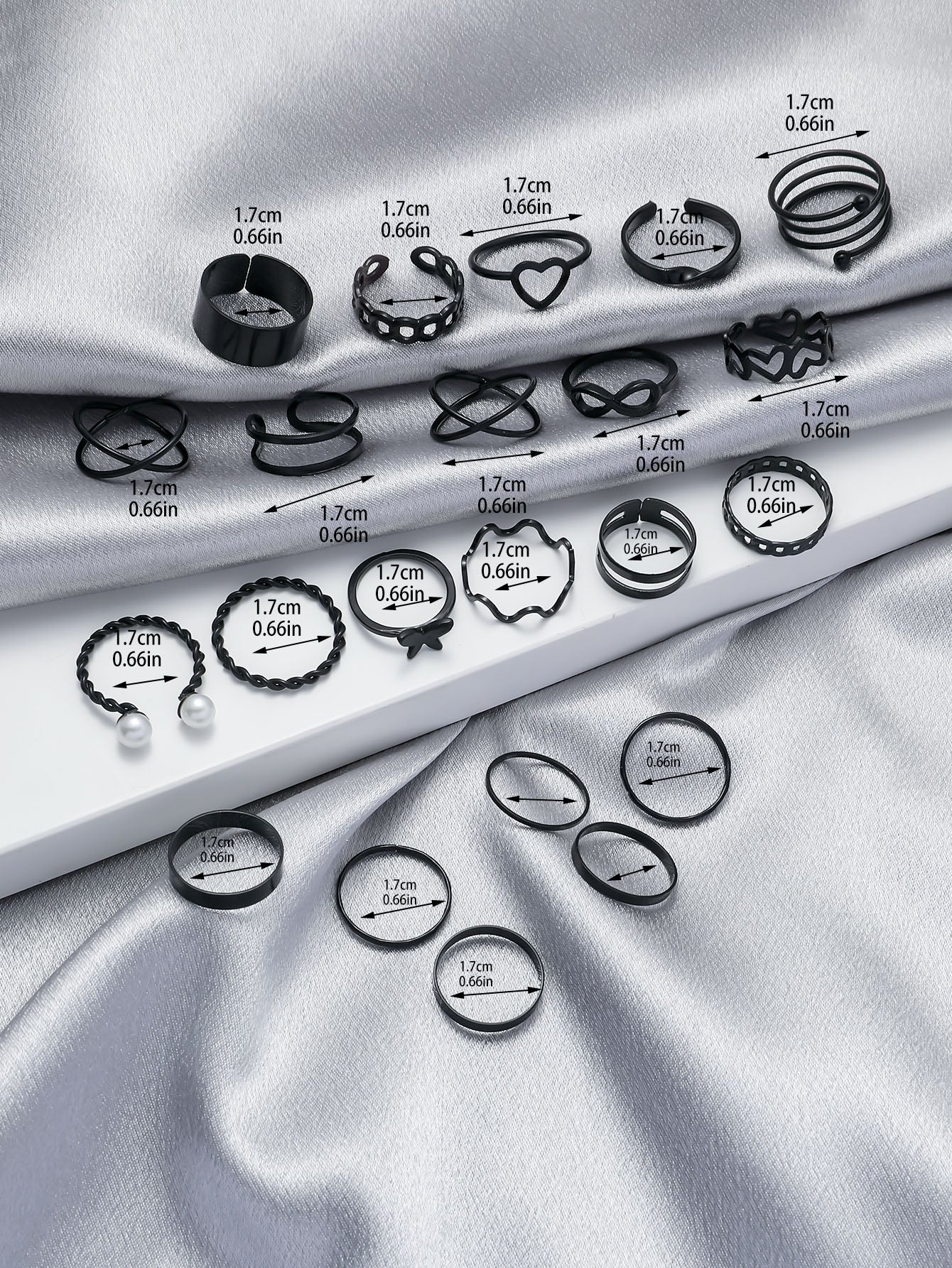 Collection of black rings on a silver fabric background with measurements indicated.