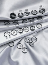 Collection of black rings on a silver fabric background with measurements indicated.