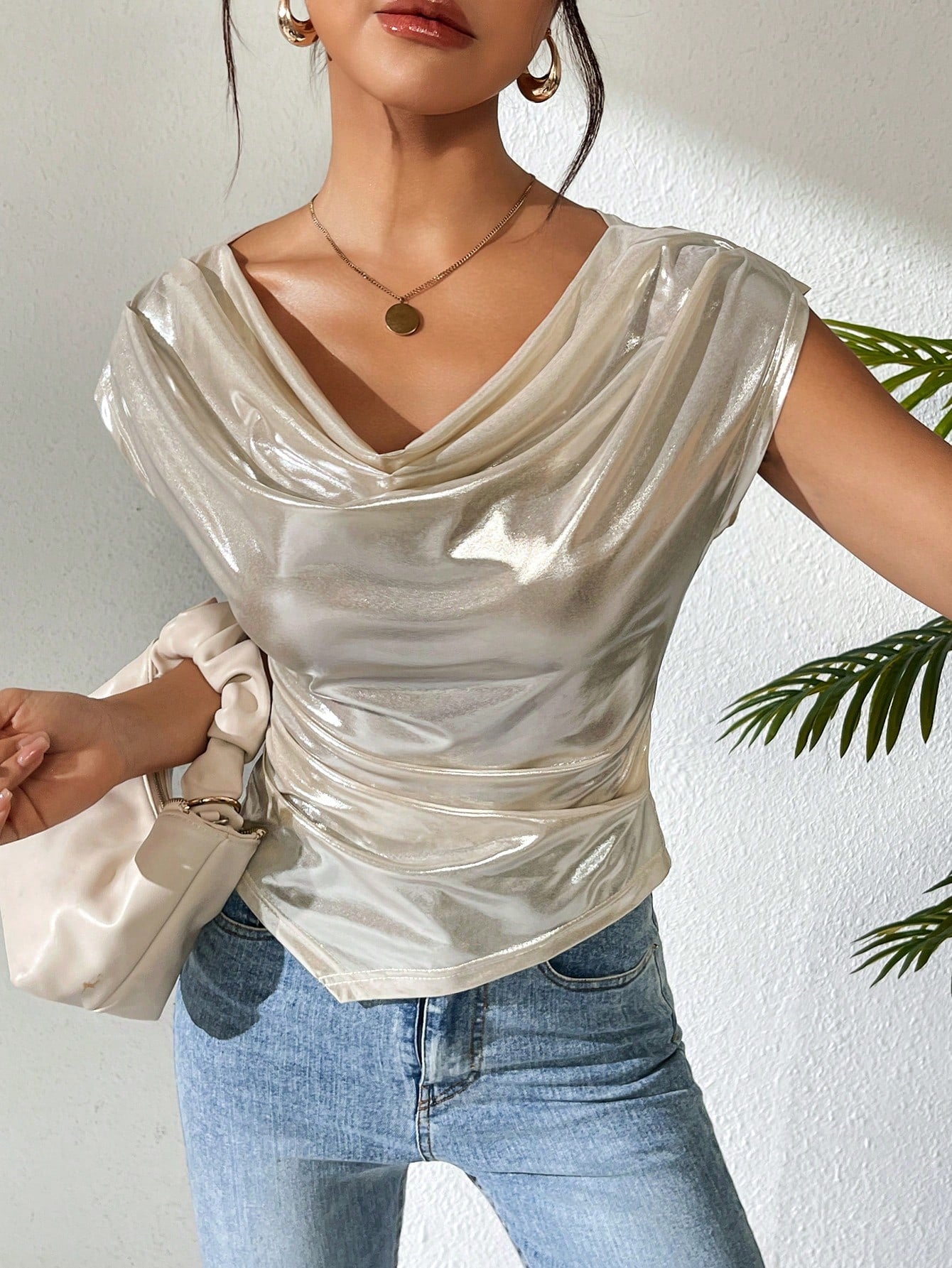 Woman wearing a shiny silver top and blue jeans with a white background