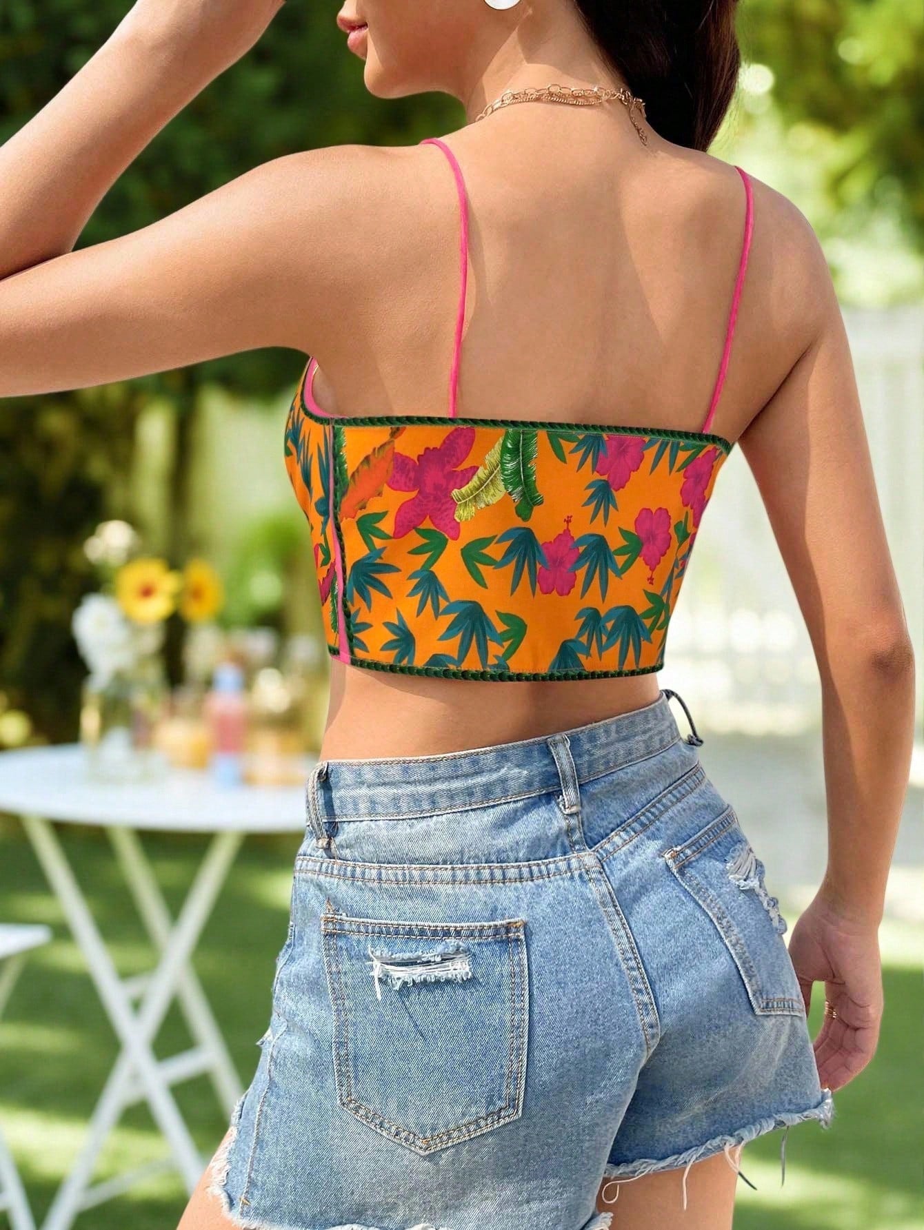Person wearing a colorful tropical print top and denim shorts outdoors.