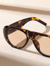 Tortoiseshell sunglasses with brown lenses on a light beige background