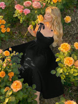 Woman in a black dress standing among flowers in a garden