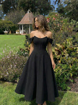 Woman wearing a black off-shoulder dress in a garden setting
