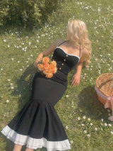 Woman in a black dress holding flowers on grass