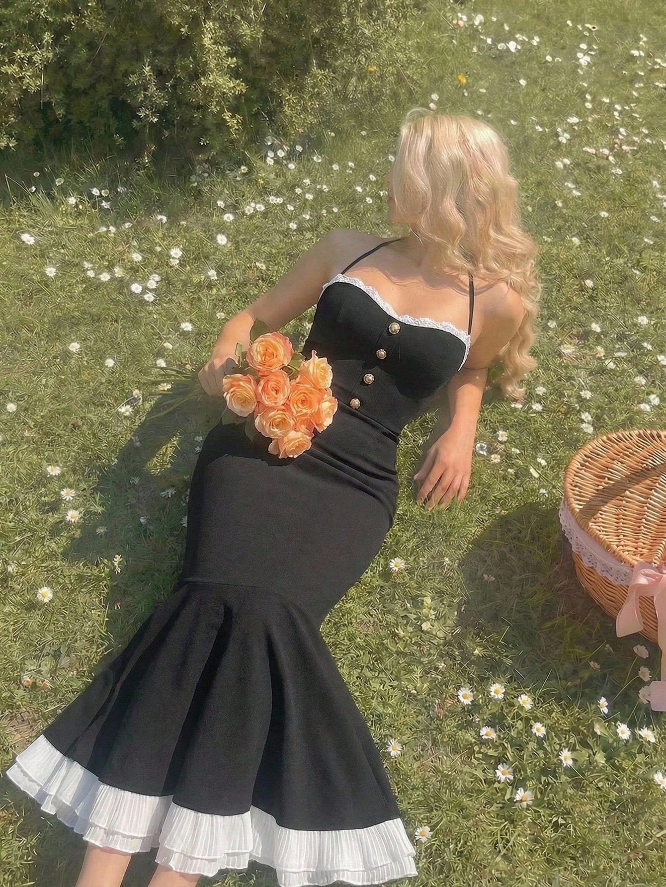 Woman in a black dress holding flowers on grass