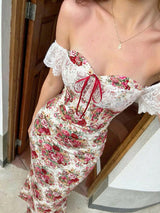 Woman wearing a floral off-shoulder dress with red accents, standing on a staircase.