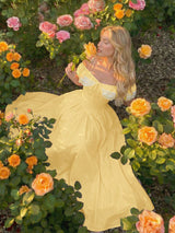 Woman in a yellow dress surrounded by flowers in a garden