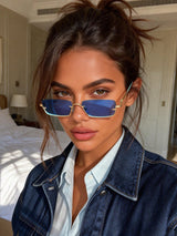 Woman wearing blue sunglasses and a denim jacket indoors.