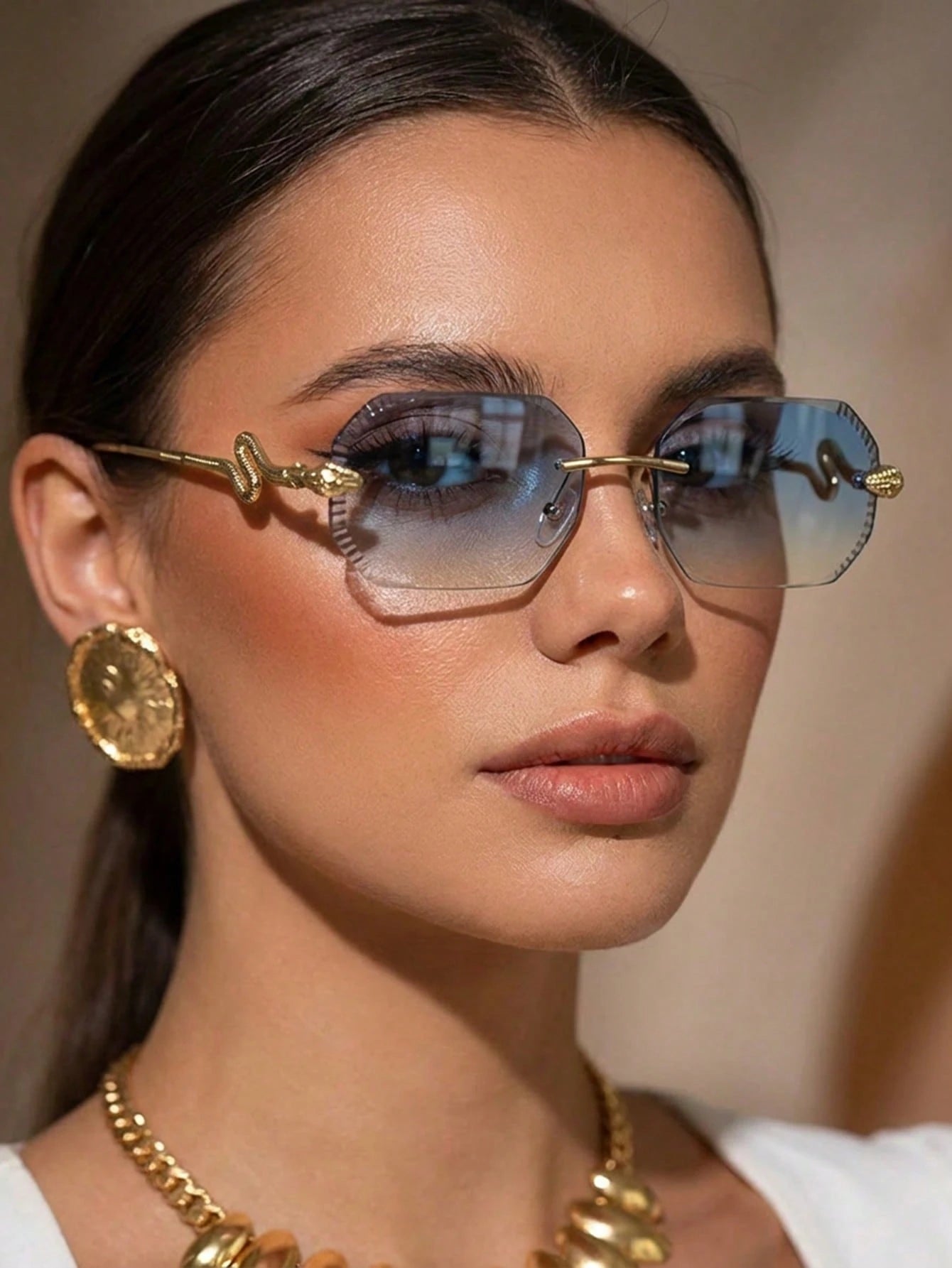 Woman wearing gold-framed sunglasses with a neutral background