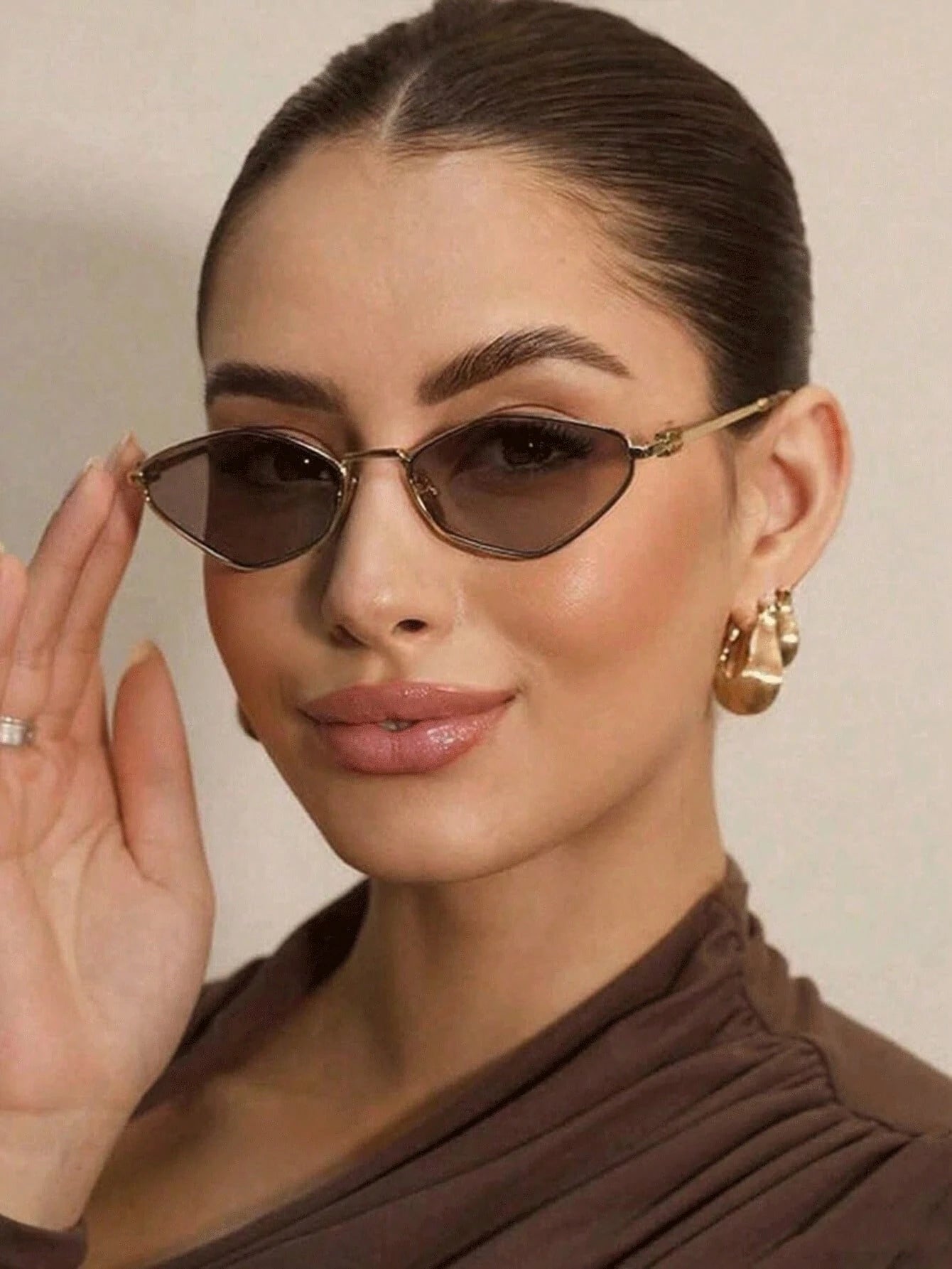 Woman wearing cat-eye sunglasses with a neutral background