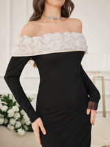 A woman wearing a black off-the-shoulder long-sleeve dress with a wide white floral ruffle trim across the neckline, posed indoors against a light neutral background.