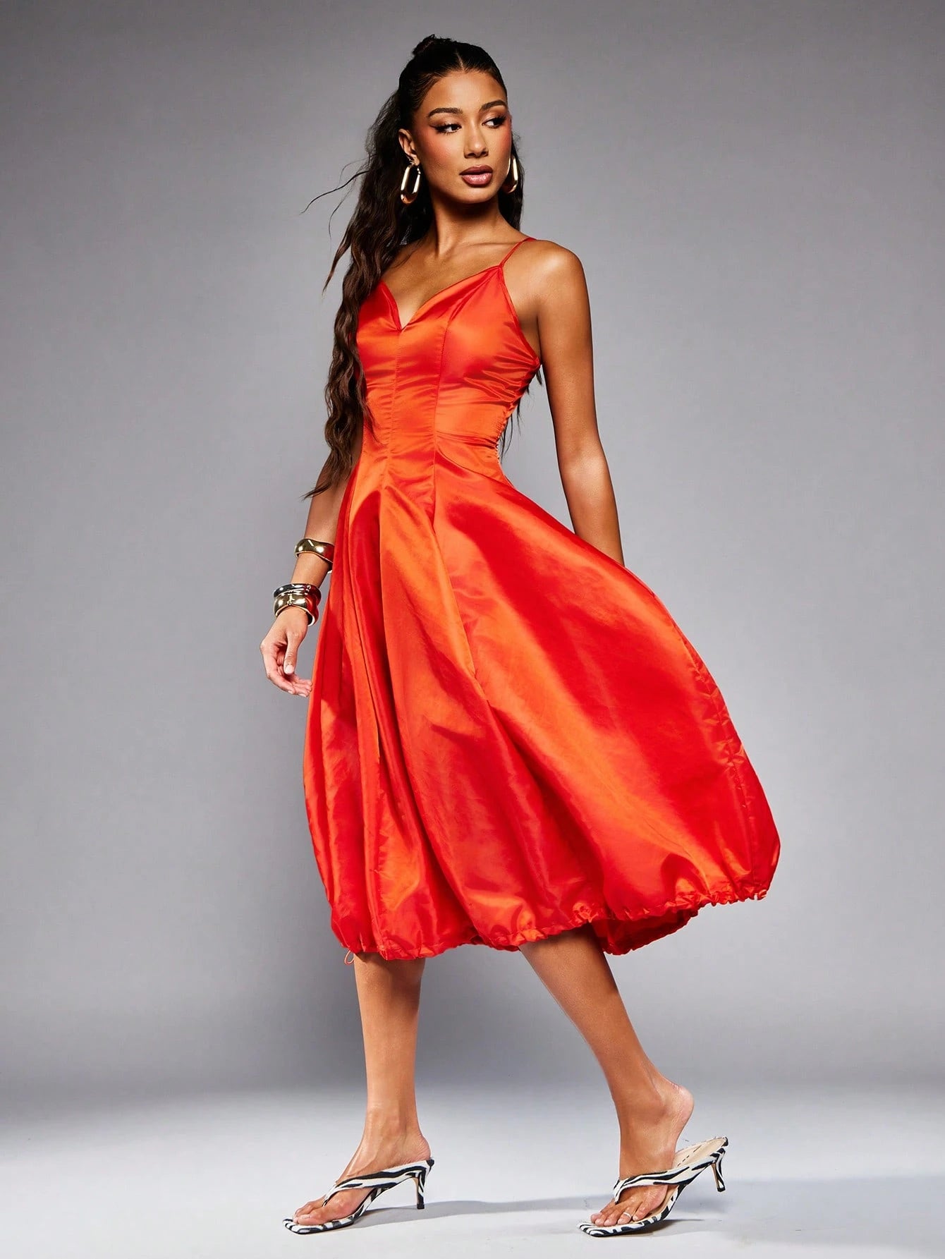 Woman wearing a bright red dress against a gray background