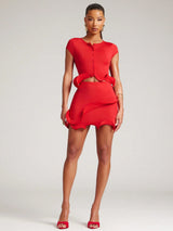 Woman wearing a red dress with cut-out design on a gray background