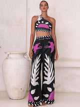 Woman wearing a black, white, and pink patterned outfit standing next to a white vase.