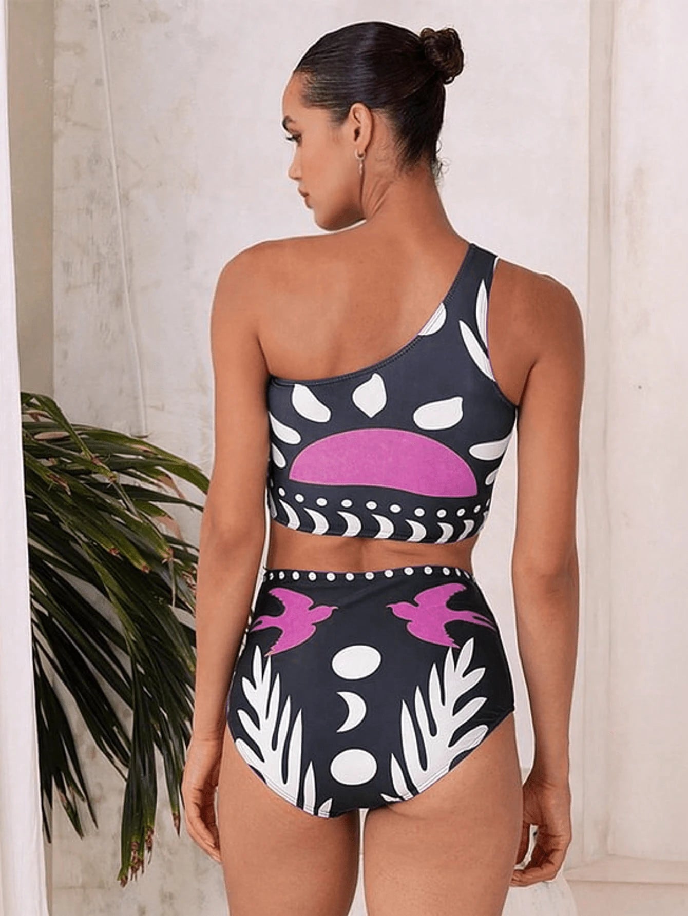 Woman wearing a black and white patterned swimsuit with pink accents.