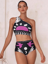 Woman wearing a black and white patterned swimsuit with purple accents on a plain background