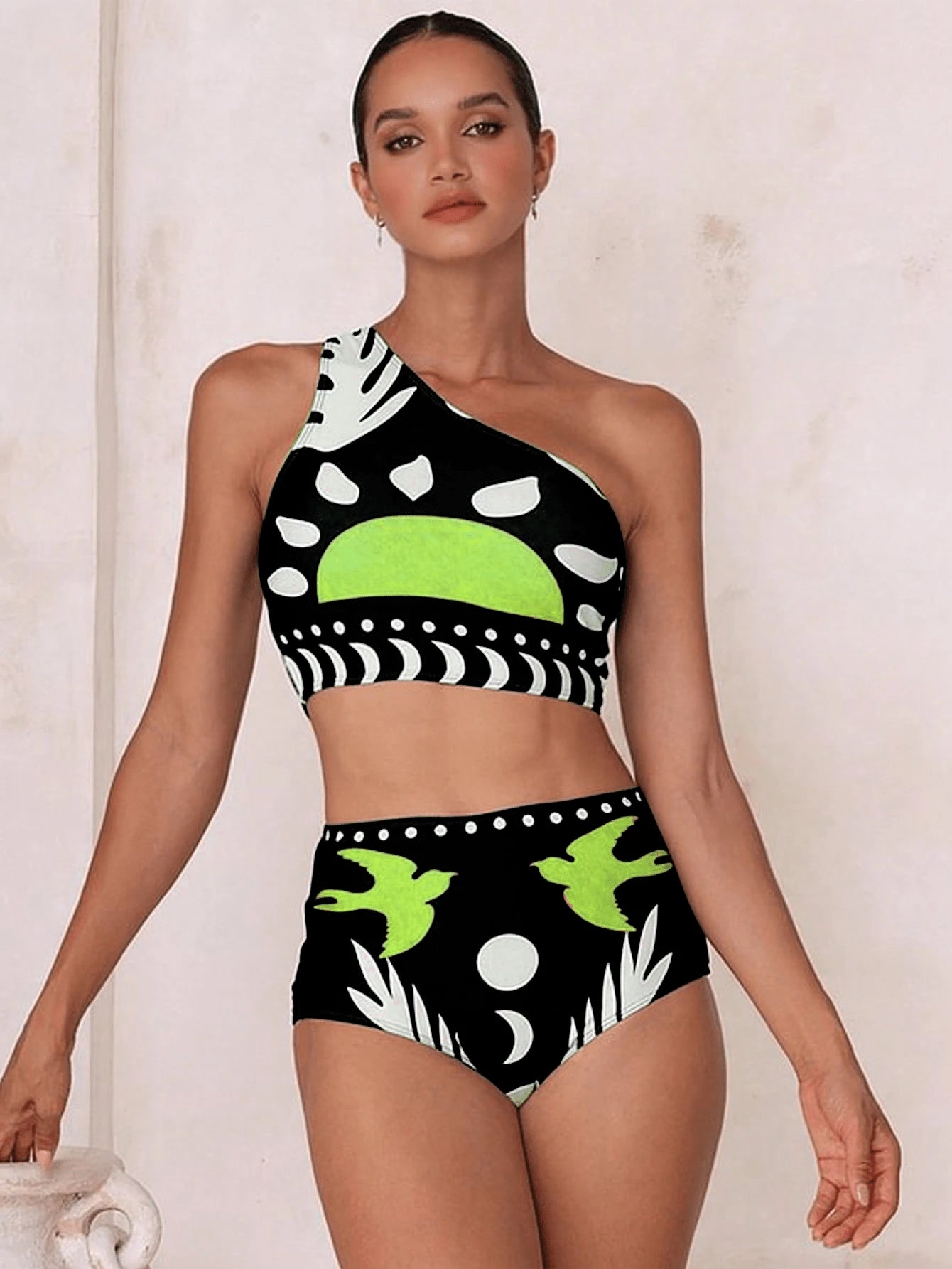 Woman wearing a black and green patterned swimsuit against a neutral background