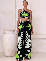 Woman wearing a black and white patterned outfit with green accents, standing next to a white vase.