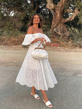 Woman in a white dress standing outdoors with trees in the background