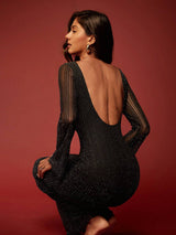 Woman wearing a black dress with sheer sleeves against a red background