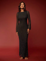 Woman wearing a black dress with sheer sleeves against a red background