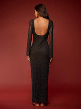 Woman wearing a black sequin dress with a deep back on a red background