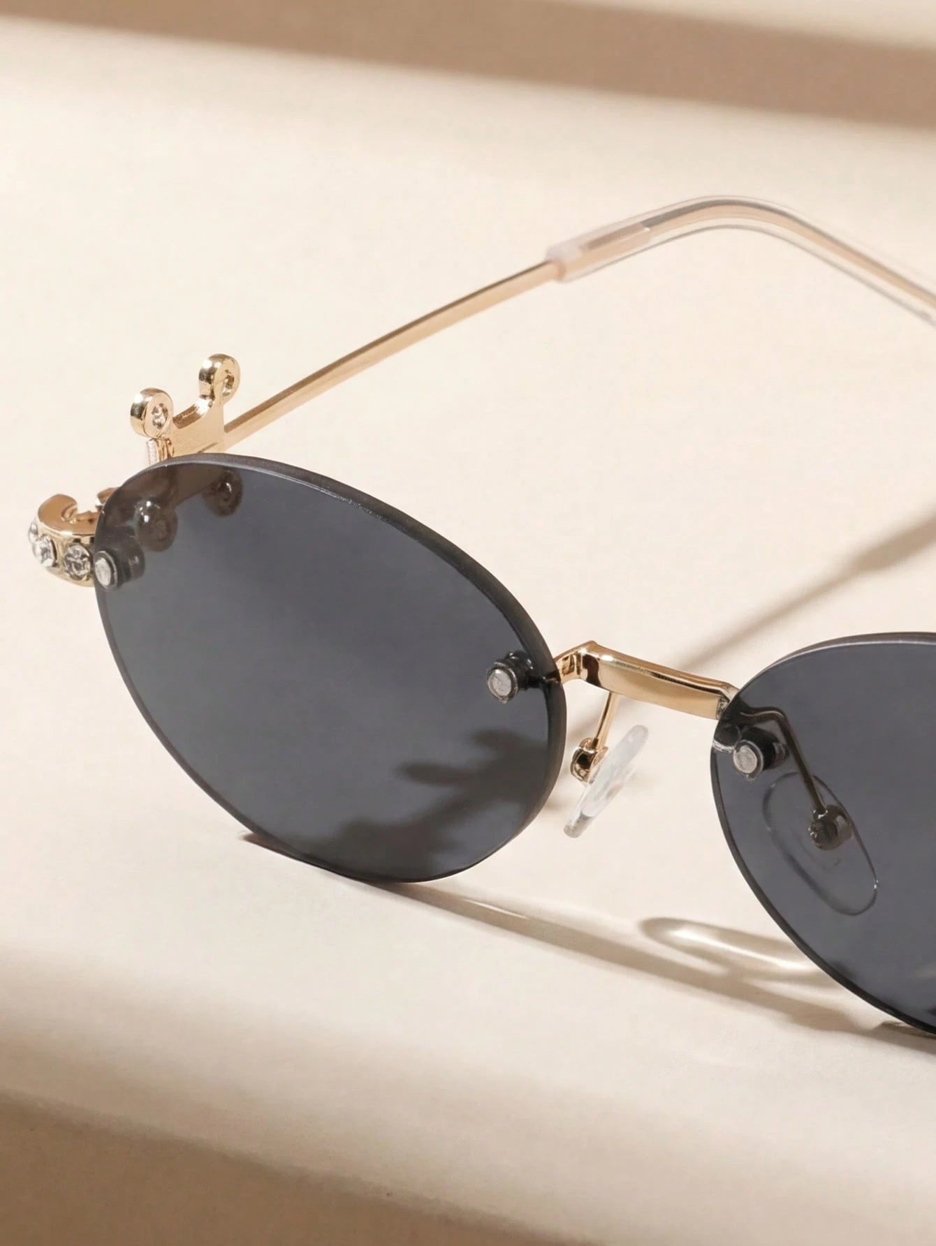 Gold-framed sunglasses with dark lenses on a beige background