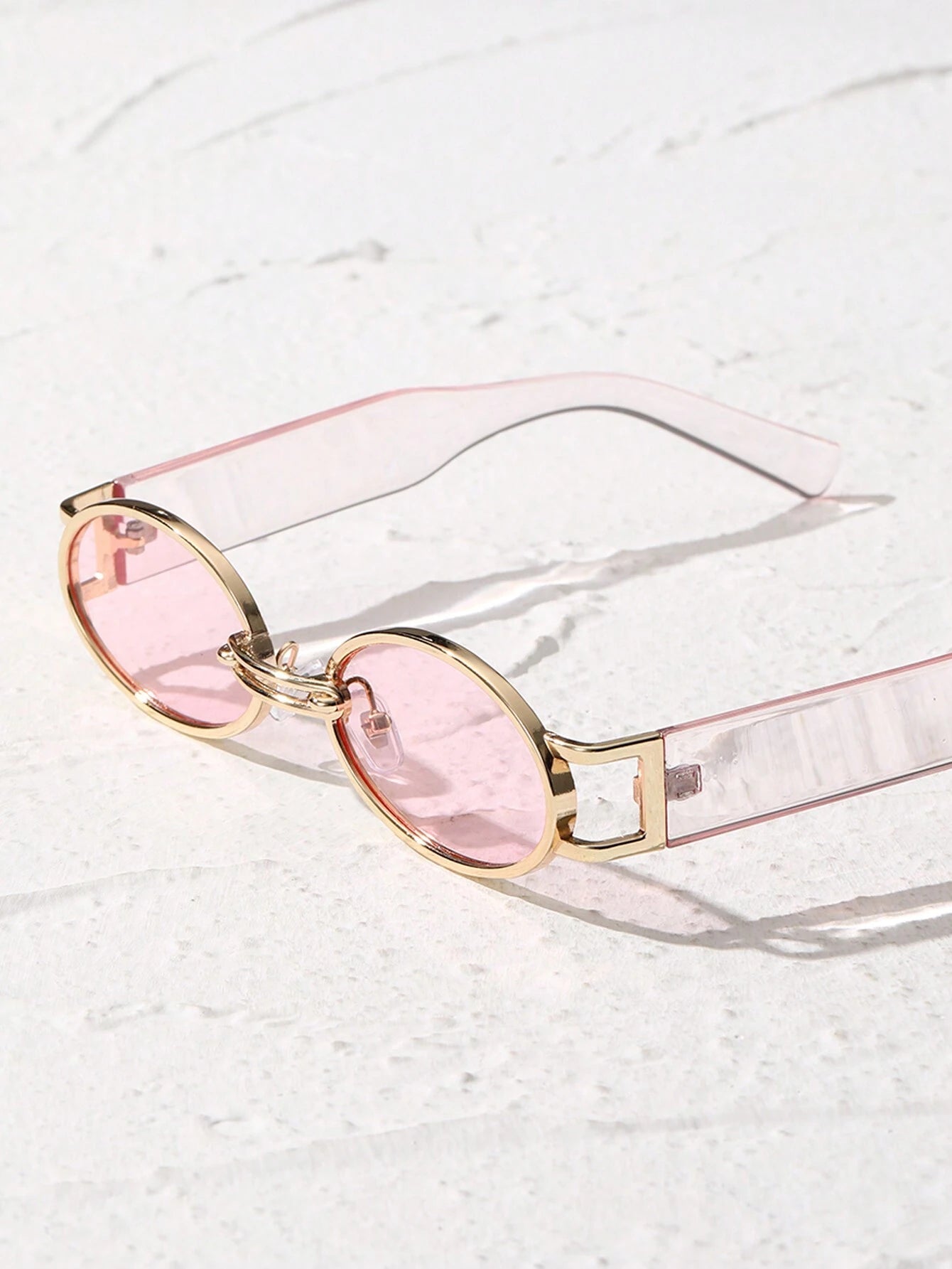 Sunglasses with pink lenses and gold frames on a light background