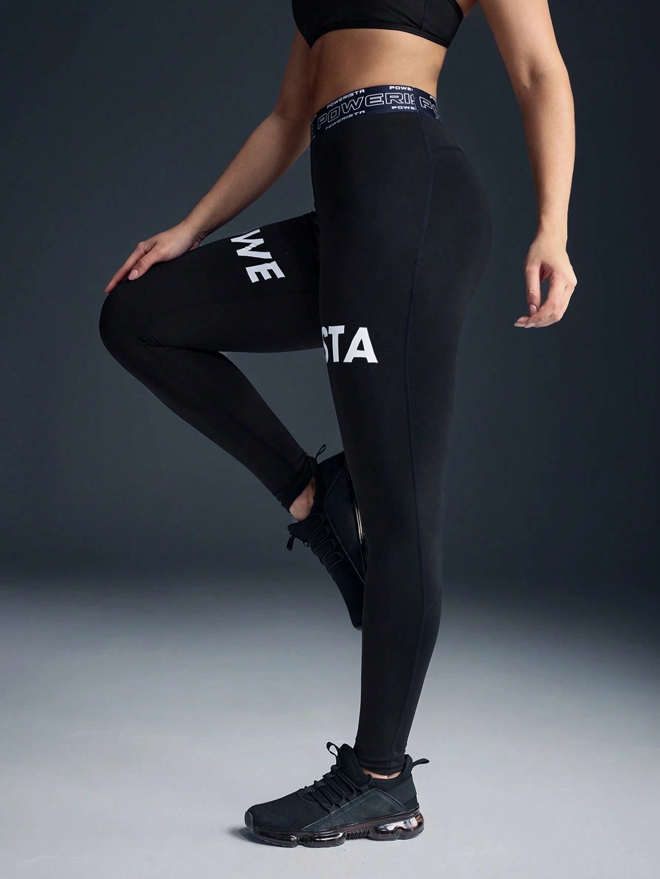 Person wearing black leggings with visible branding on a dark background