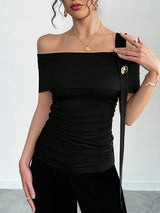Woman wearing a black off-shoulder top with a plain background