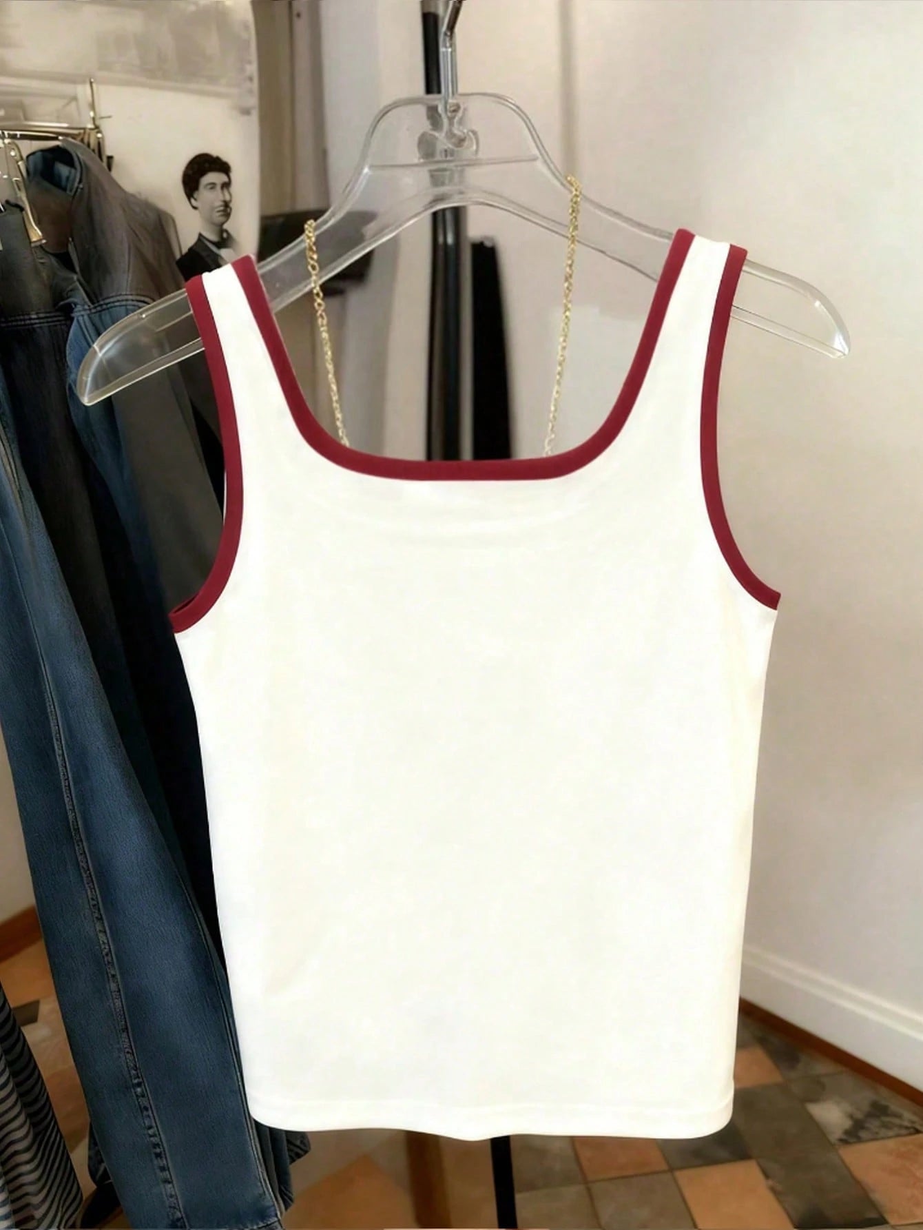 White tank top with red trim on a hanger against a neutral background