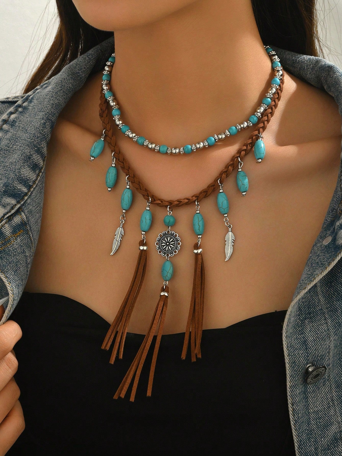 Necklace with turquoise beads and tassels on a person wearing a denim jacket.