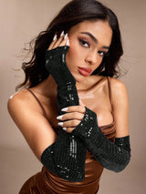 Woman wearing black beaded gloves against a beige background