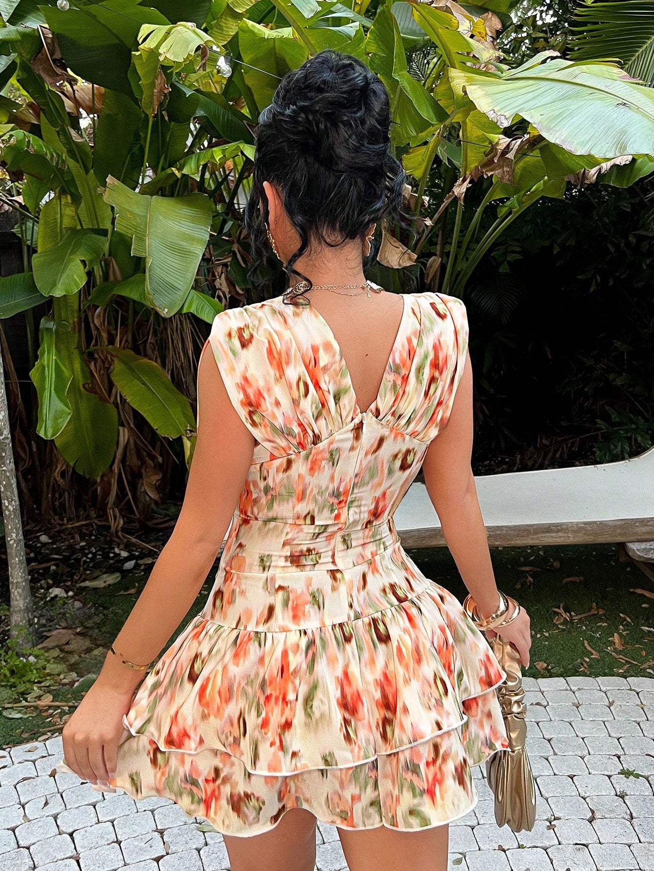 Woman wearing a floral dress in an outdoor setting with greenery.