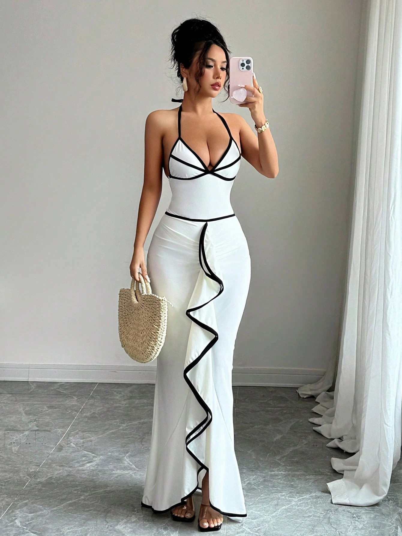 Woman in a white and black outfit taking a mirror selfie.