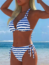 Woman wearing a blue and white striped bikini set on a beach.