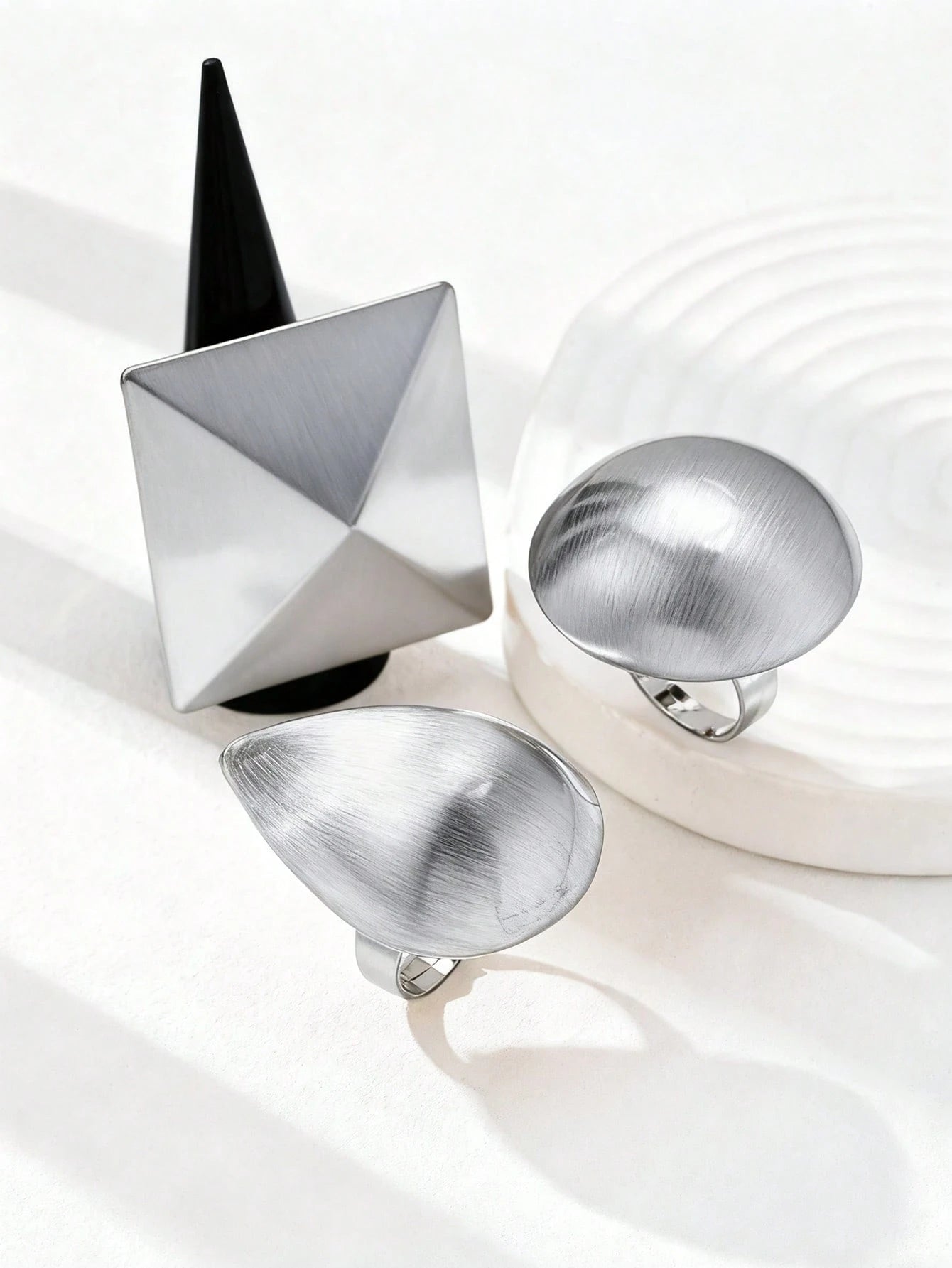 Three metallic jewelry pieces on a white background